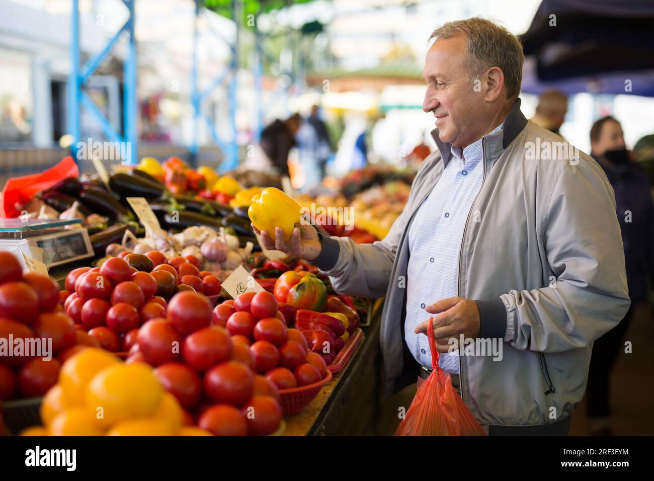 Uomo che acquista peperoni in gregrocery Foto Stock