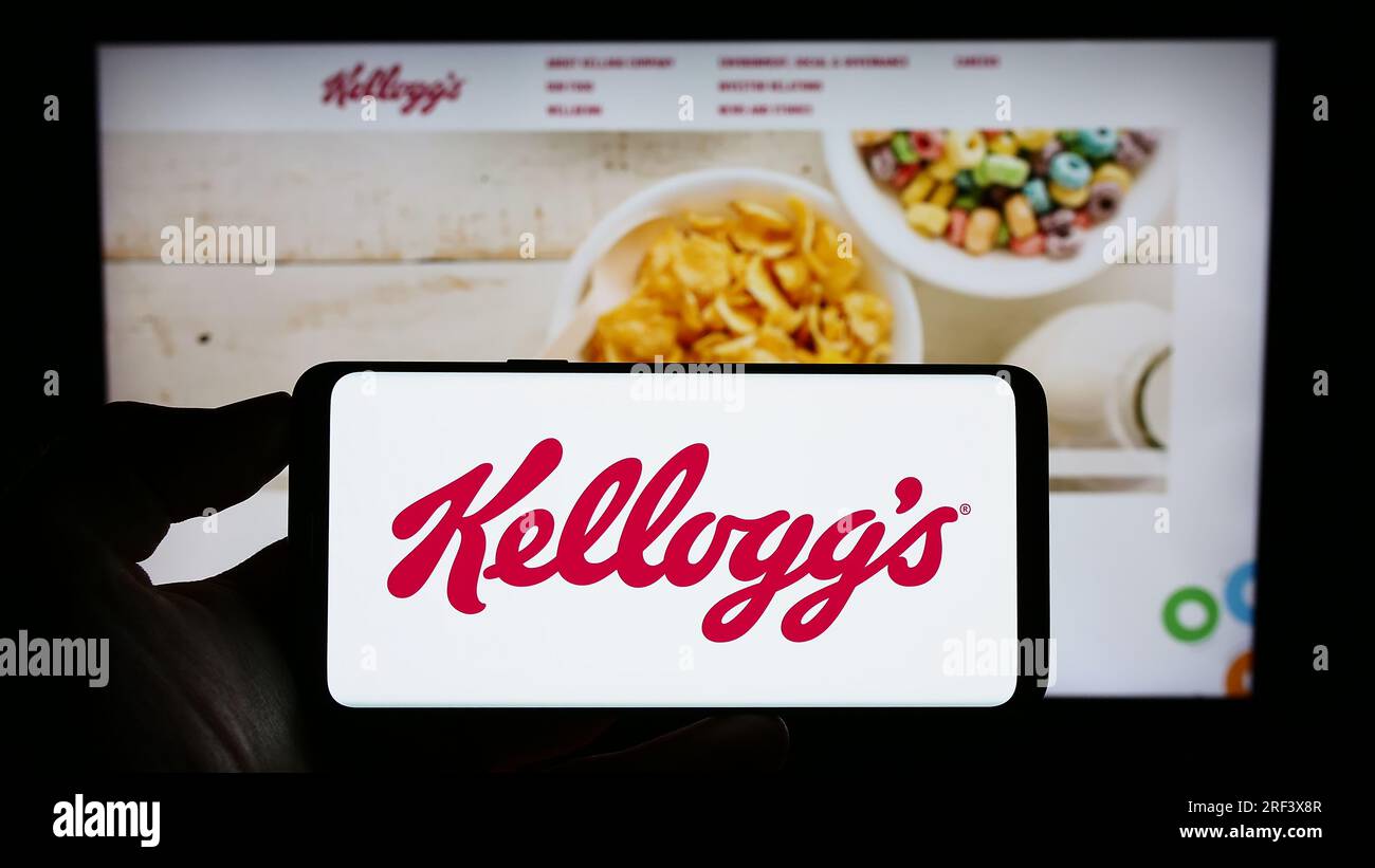 Persona in possesso di un cellulare con il logo dell'azienda statunitense The Kellogg Company (Kellogg's) sullo schermo di fronte alla pagina Web. Concentrarsi sul display del telefono. Foto Stock