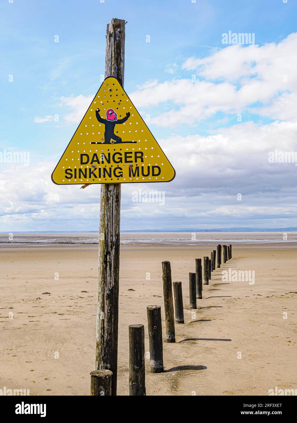 Un triangolo d'allarme sulla spiaggia del Weston super Mare nel Somerset ha dato una faccia da cartone animato per avvertire del fango che affonda Foto Stock