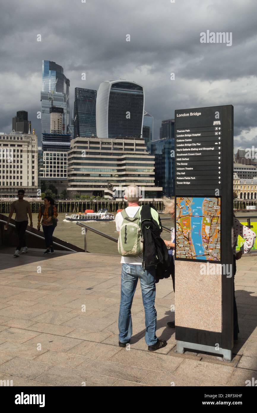 Nuvole di tempesta che si radunano sulla City di Londra e un uomo dai capelli grigi che guarda lo skyline e il fiume Tamigi, Londra, Inghilterra, Regno Unito Foto Stock