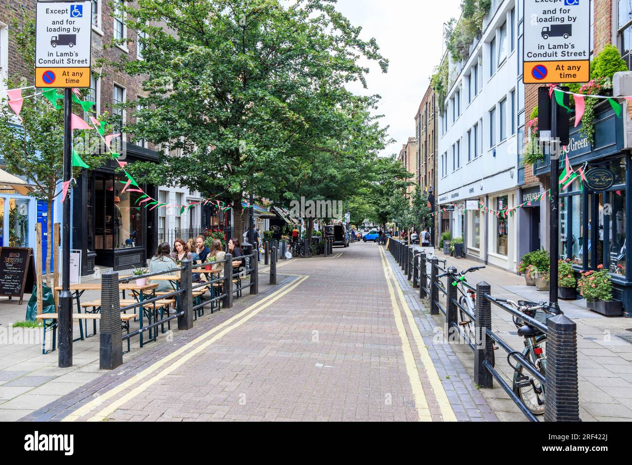 Una vista lungo Lamb's Conduit Street a Holborn, Londra, Regno Unito, con persone che mangiano all'aperto nei caffè e ristoranti di maggio Foto Stock