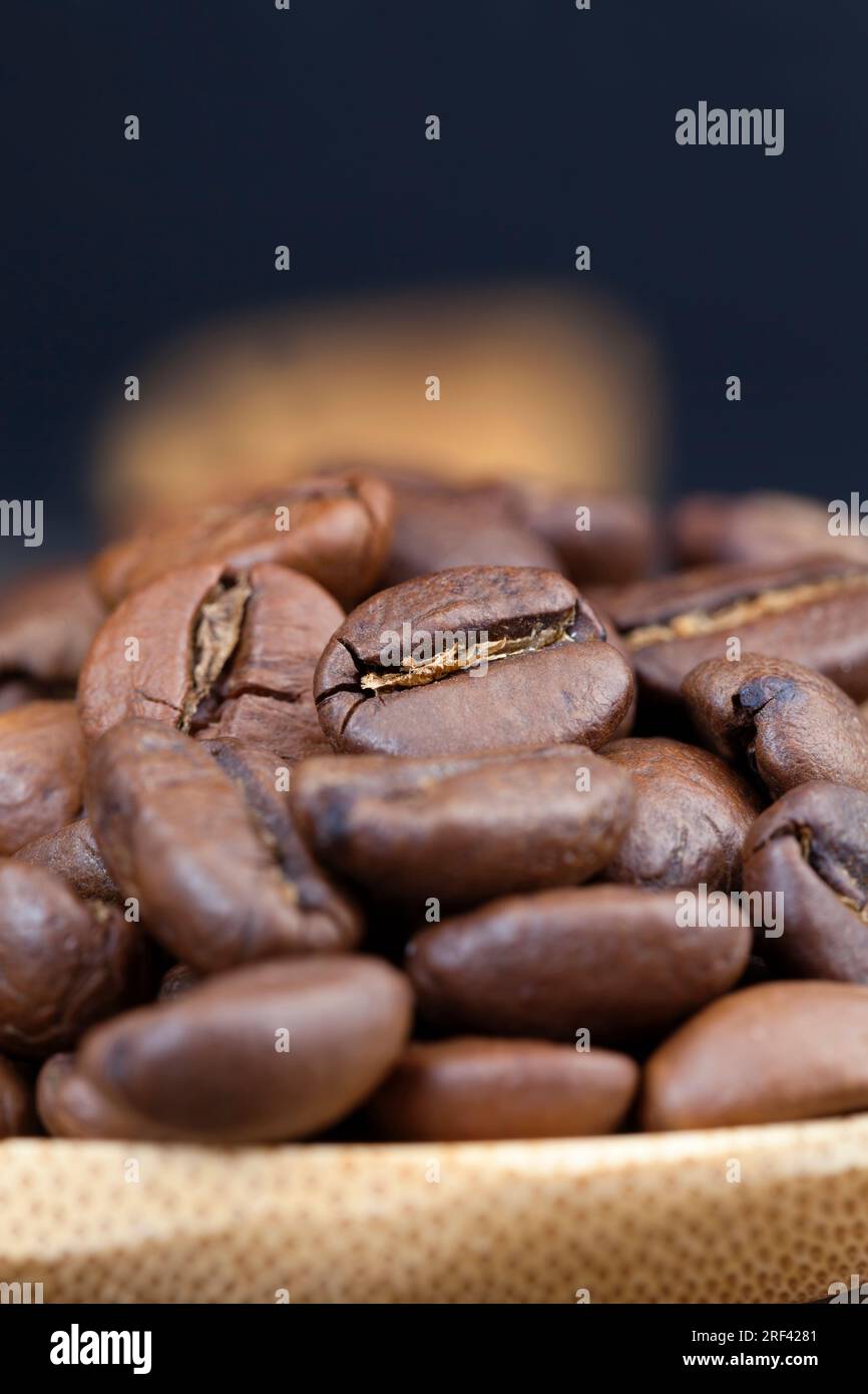 chicchi di caffè per la produzione di delizioso caffè in un misurino a base di bambù, chicchi di caffè in forma intera per macinare, chicchi di caffè aromatici Foto Stock