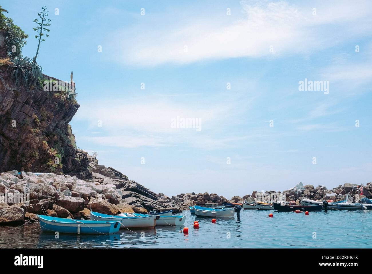 Cinque Terre, Italia - attracco a Riomaggiore con piccole imbarcazioni. Cittadina di mare sulla Riviera Italiana. Spiaggia rocciosa al sole. Vacanze estive backgr Foto Stock