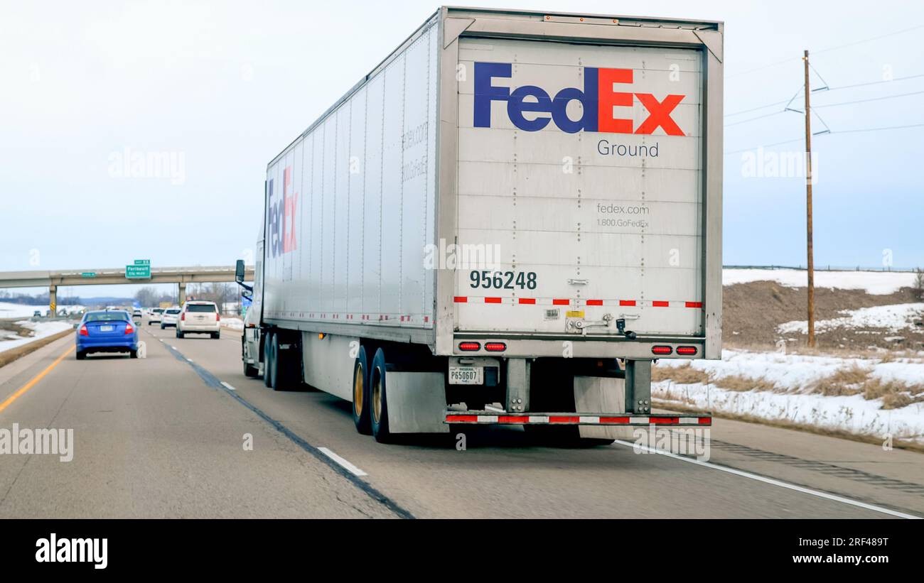 FARIBAULT, Minnesota - 5 marzo 2023: Fed Ex semi Truck Driving on Freeway, visto attraverso il parabrezza di un'auto in una giornata nuvolosa. Foto Stock