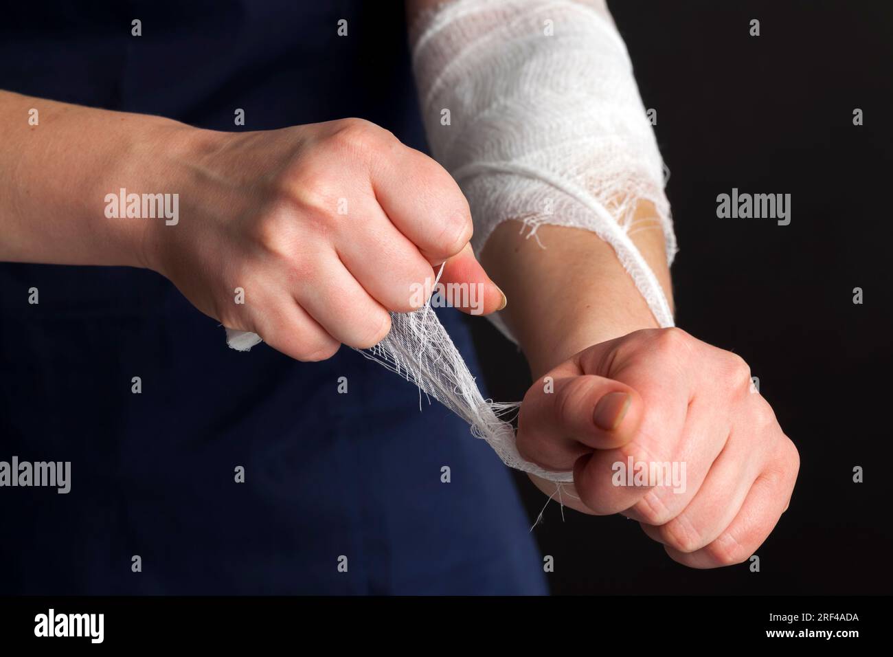 benda bianca medica nelle mani di un medico femminile, un uomo in abbigliamento medico tiene una benda bianca nelle sue mani per trattare urti, lesioni e altro Foto Stock