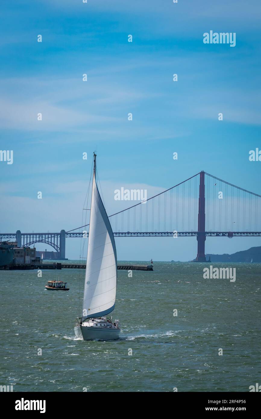 Foto verticale di una barca che naviga con il Golden Gate Bridge sullo sfondo a San Francisco, California, USA Foto Stock