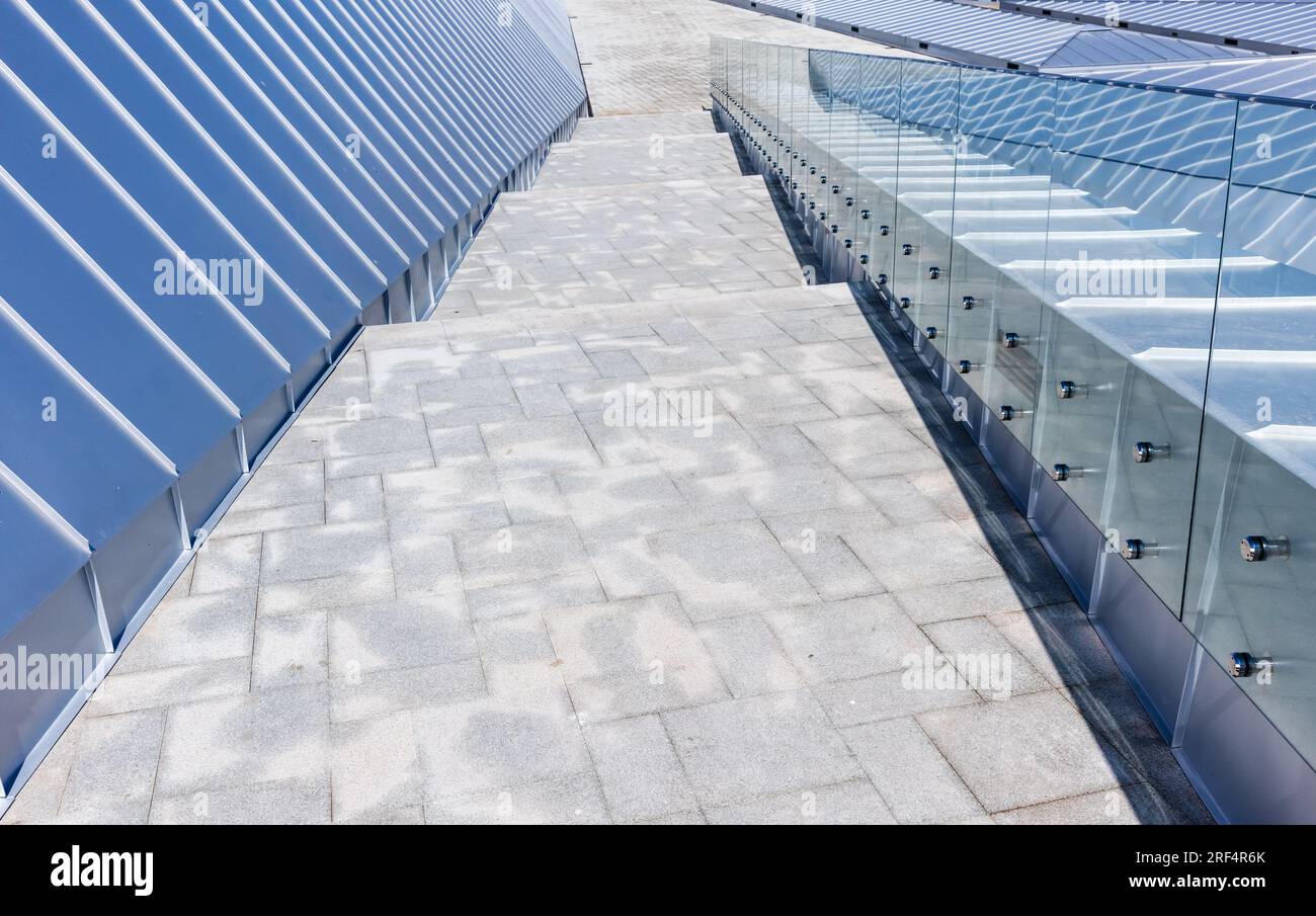 Sfondo di architettura moderna astratta con nuovo tetto lucido realizzato con piastre in acciaio inossidabile, corrimano e scalinata in pietra Foto Stock