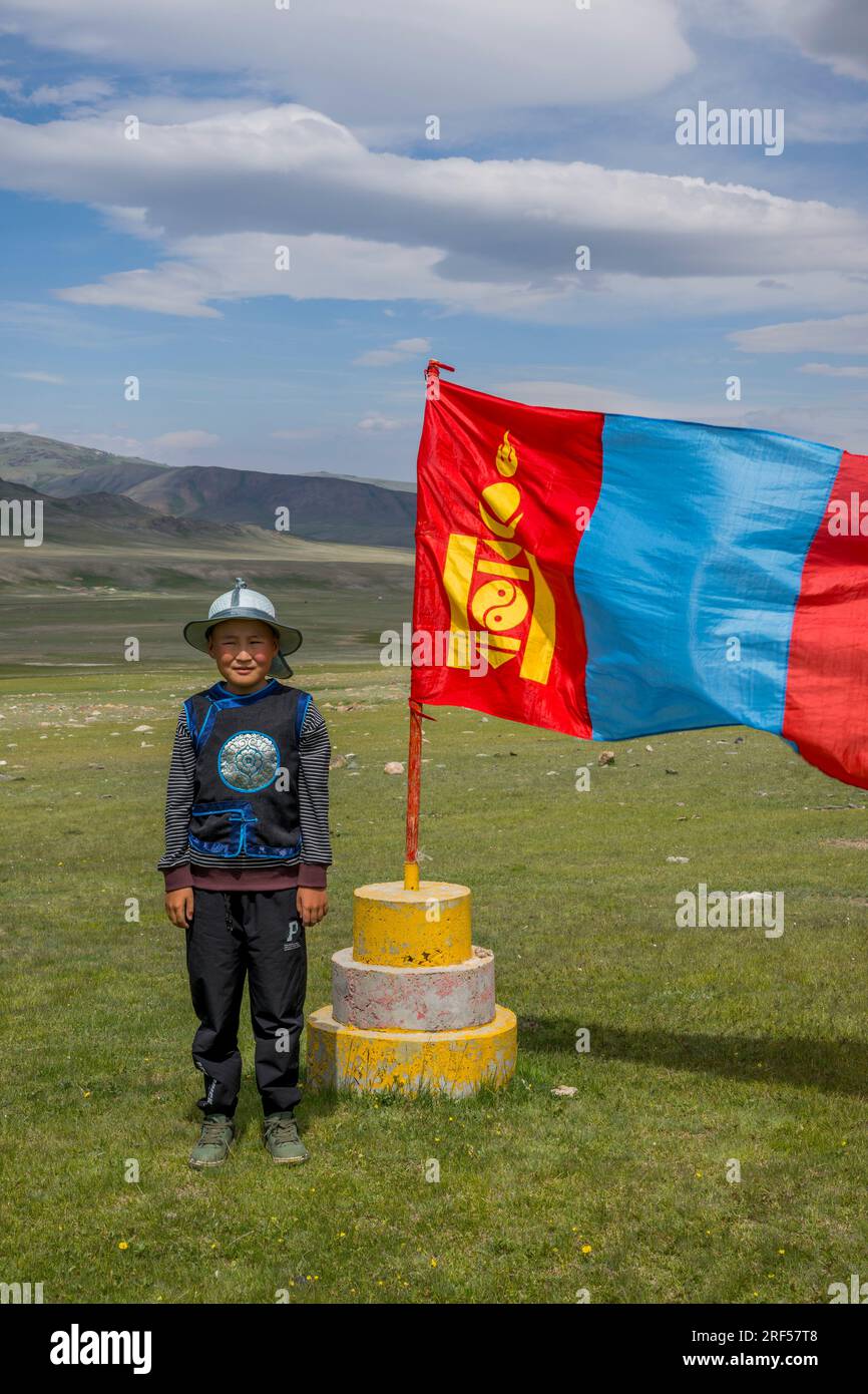 Un ragazzo sta posando davanti alla bandiera nazionale mongola nel luogo di un festival locale di Naadam nella valle del fiume Sagsai, una valle remota in alta Foto Stock