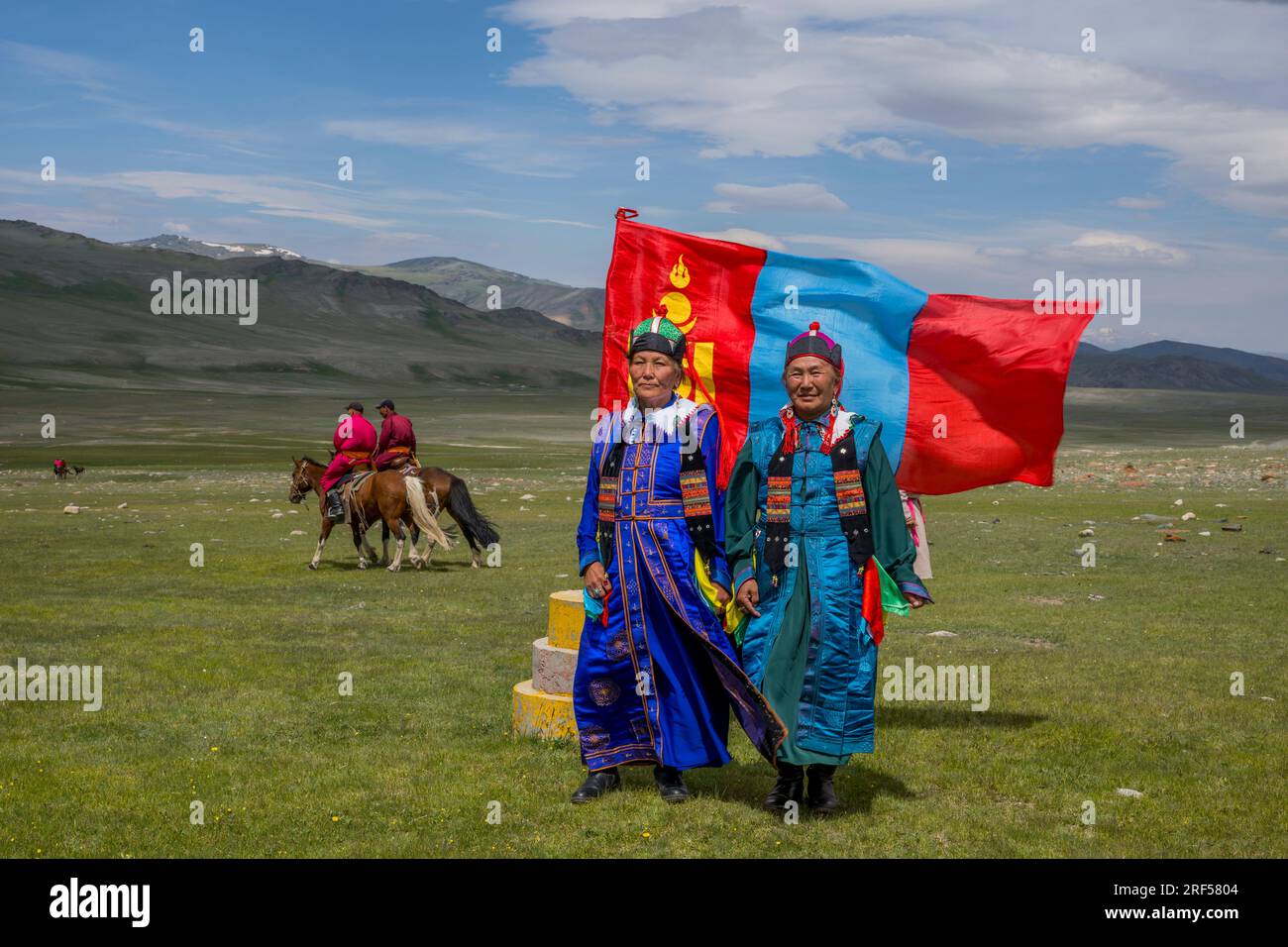 Due donne in posa di fronte alla bandiera nazionale mongola presso il luogo di un festival locale di Naadam nella valle del fiume Sagsai, una valle remota nell'alt Foto Stock