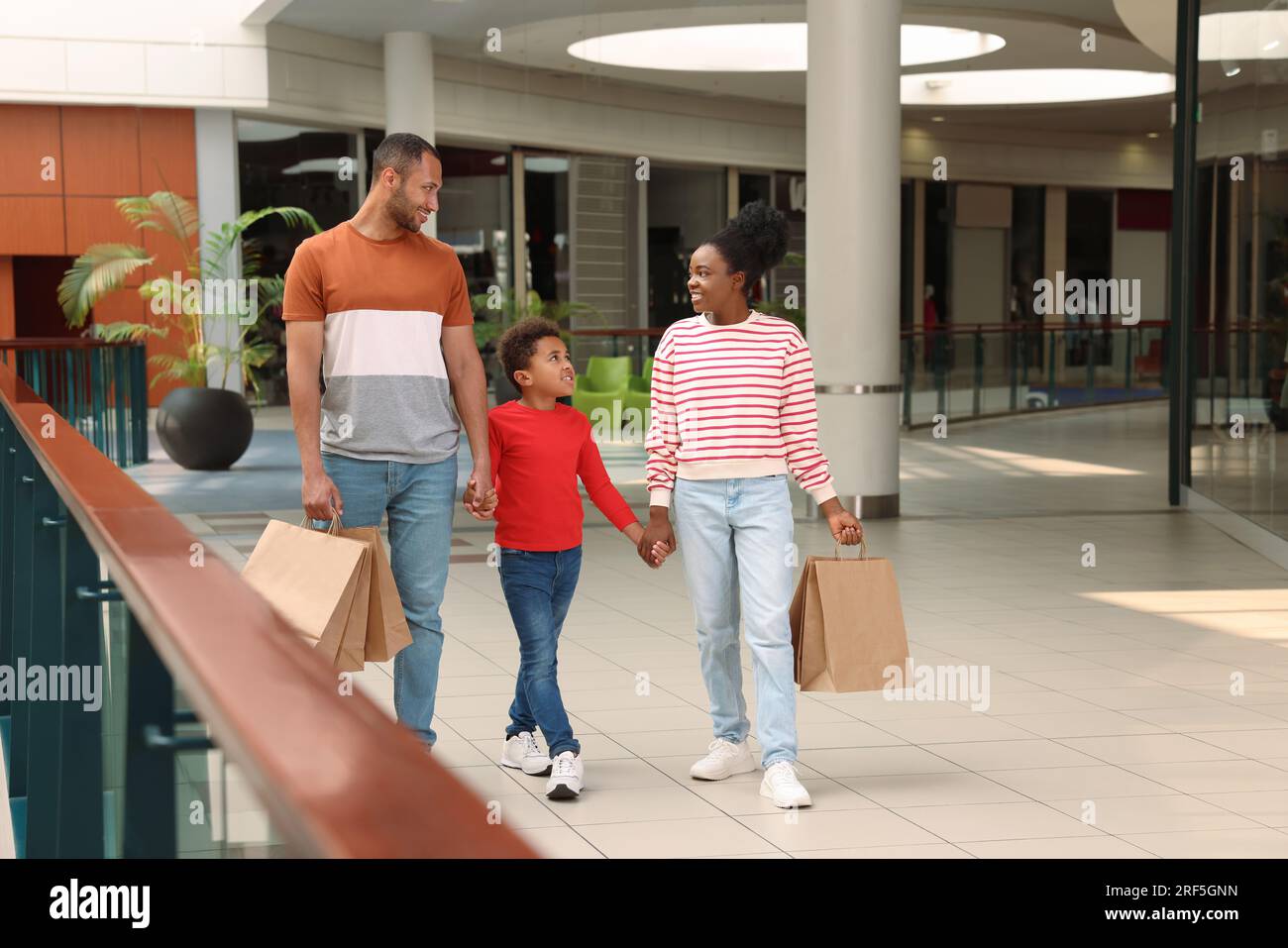 Shopping per famiglie. Genitori e figlio felici con gli acquisti al centro commerciale Foto Stock