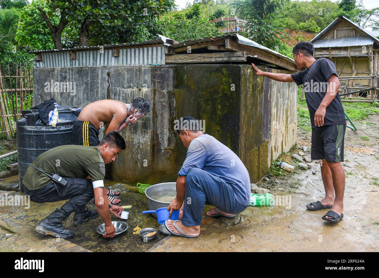 I volontari tribali fanno un bagno e lavano i piatti dopo pranzo fuori da una cucina comunitaria nel villaggio di Dampi a Churachandpur, Manipur. Il distretto di Churachandpur e l'intera area collinare sono sede di molte tribù prevalentemente cristiane. Questi giovani, che si assumono la responsabilità dell'autodifesa, hanno un'età compresa tra i 13 e i 30 anni e hanno scelto di sacrificare l'istruzione, le attività agricole e le notti pacifiche per proteggere i confini del loro villaggio con armi e armi. (Foto di Biplov Bhuyan/SOPA Images/Sipa USA) Foto Stock