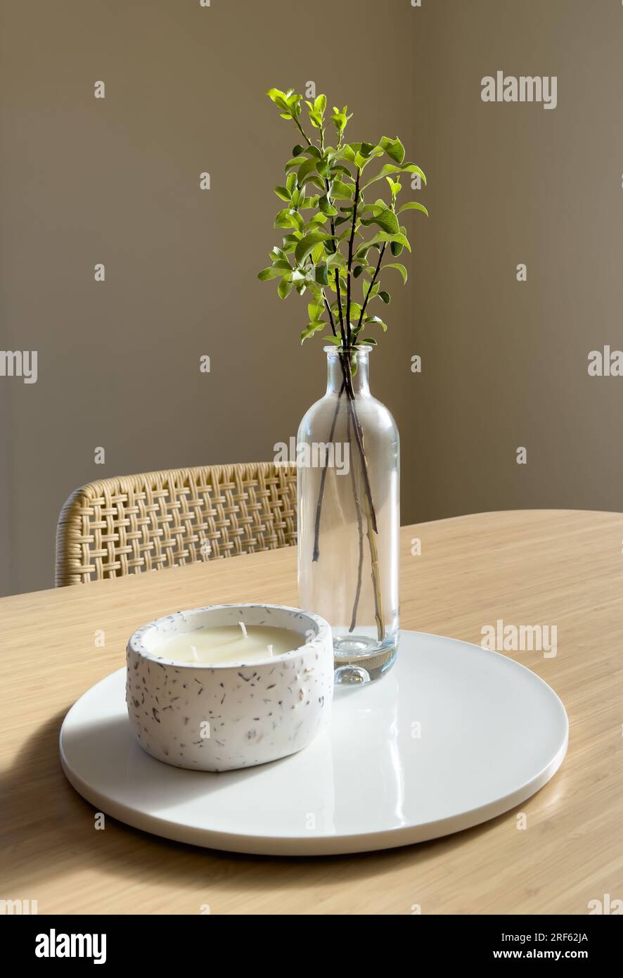 Vaso di vetro dallo stile scandinavo moderno con foglie verdi e candela su un tavolo di bambù con spazio per la copia Foto Stock