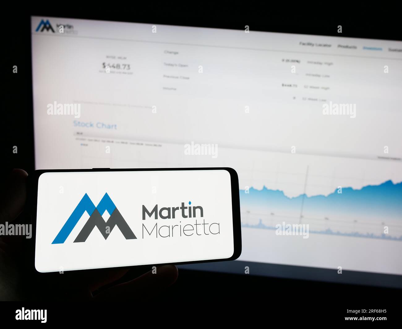 Persona che possiede un telefono cellulare con il logo dell'azienda americana Martin Marietta Materials Inc. Sullo schermo davanti alla pagina Web. Concentrarsi sul display del telefono. Foto Stock