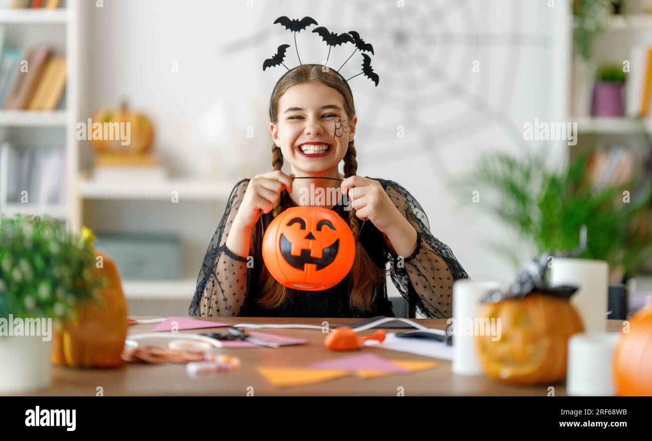 Adorabile adolescente con zucca intagliata. Ragazza felice che si prepara per Halloween. Divertente ragazzo a casa. Foto Stock