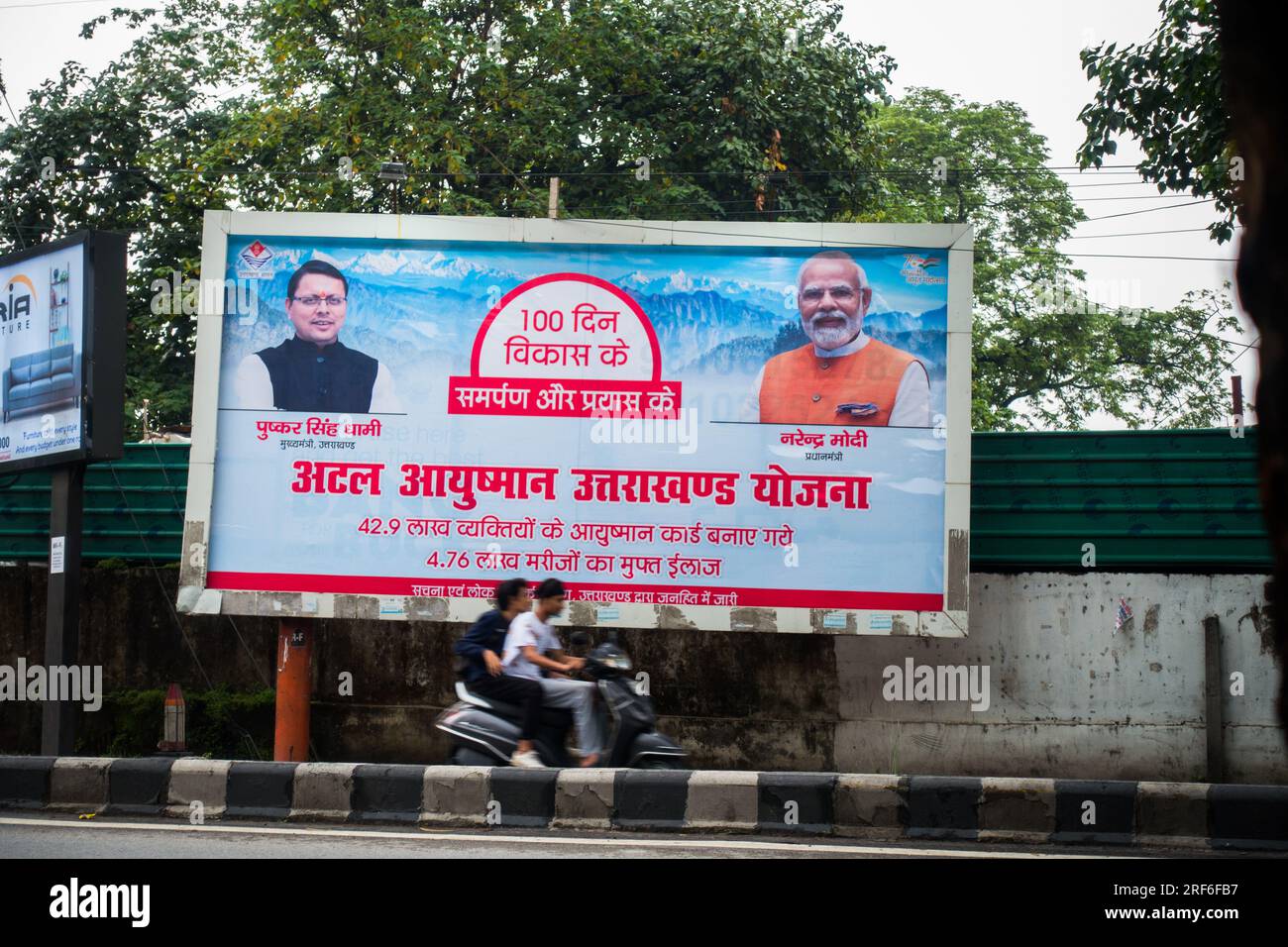 28 giugno 2023.Uttarakhand India.Hindi cartellone sui bordi delle strade di Uttarakhand, che mette in evidenza Atal Ayushman Uttarakhand Yojana, con il capo ministro D. Foto Stock