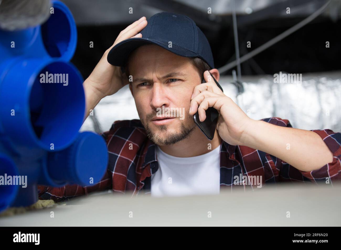 tecnico di ventilazione maschile che parla per telefono Foto Stock