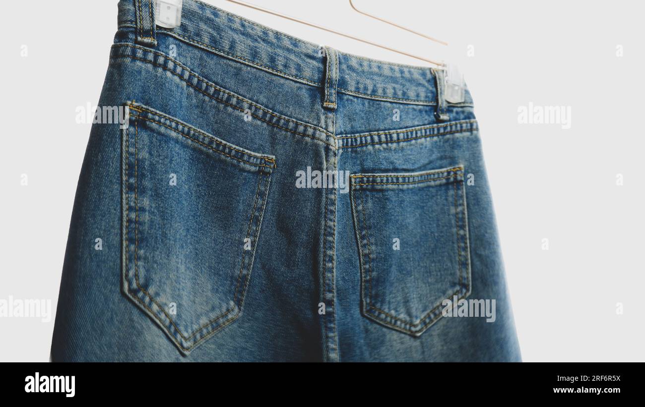 Primi piani di jeans blu appesi a uno sfondo bianco Foto Stock