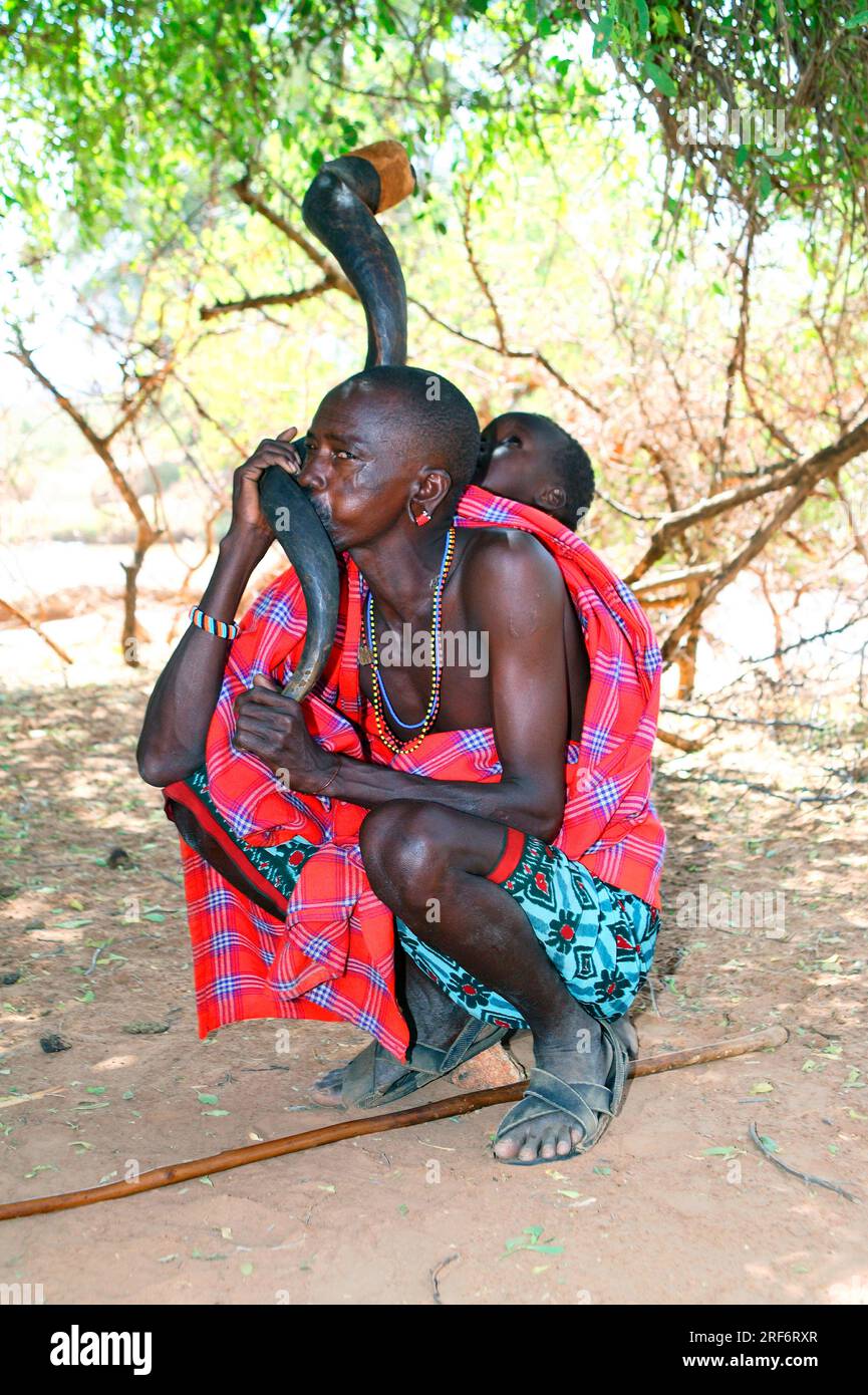 Samburu uomo con bambino, tribù Samburu, Parco Nazionale Samburu, riserva di caccia Samburu, corno kudu, strumento musicale, strumento a fiato, musica, fare Foto Stock