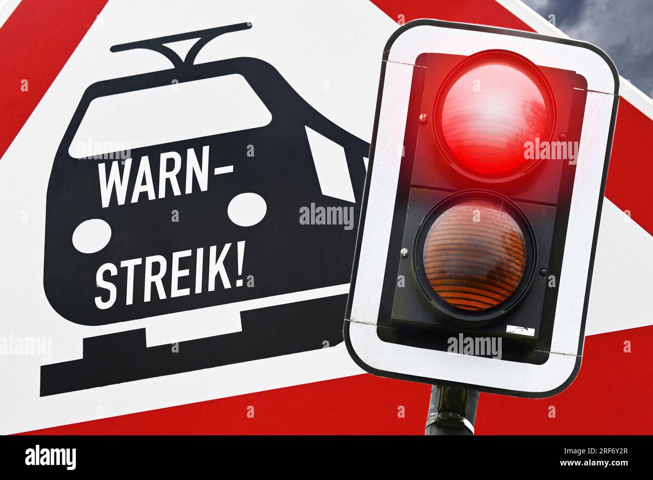 FOTOMONTAGE, Bahnschild mit Aufschrift Warnstreik und rotes Haltesignal Foto Stock