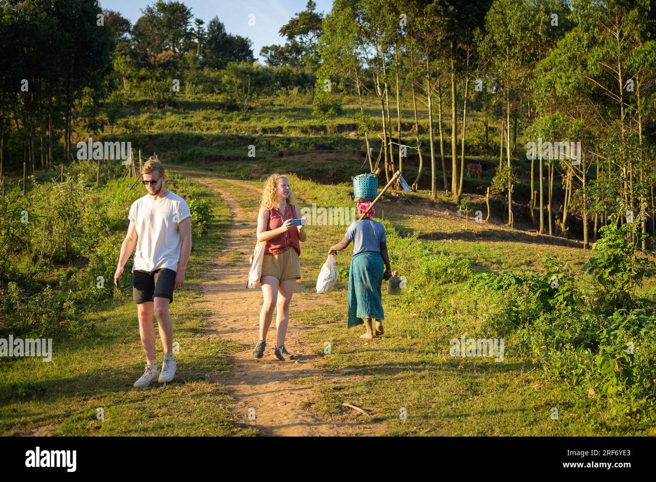 Lago Bunyonyi, Uganda - 15 giugno 2022: Due turisti e un passaggio autoctono su un sentiero su un'isola del lago Bunyonyi Foto Stock