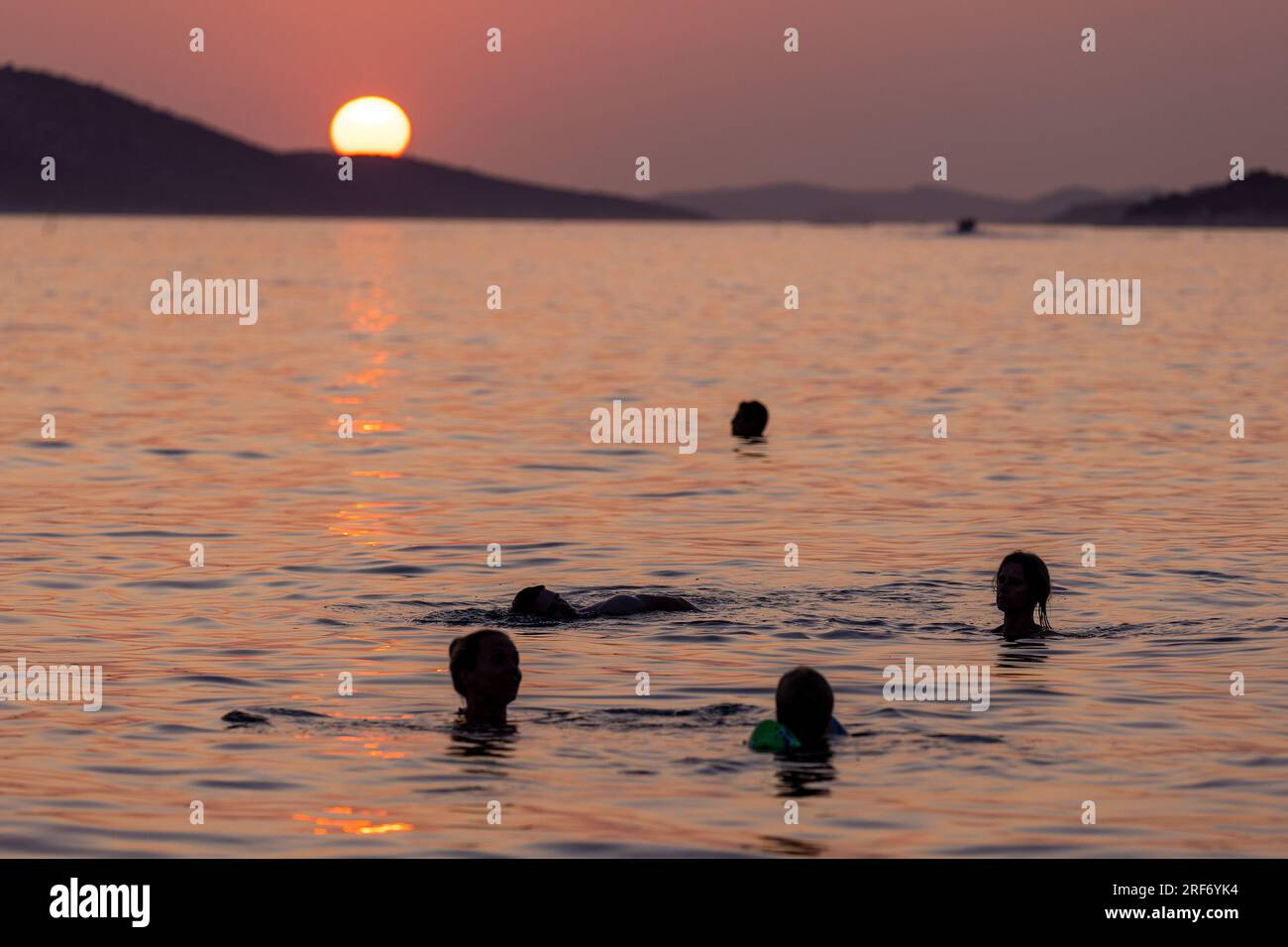 Tramonto sul mare Adriatico in Croazia, con la gente che nuota Foto Stock