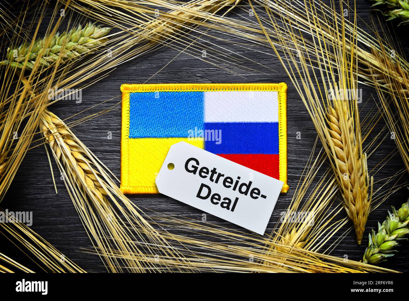FOTOMONTAGE, Die Fahnen von Ukraine und Russland umgeben von Kornähren und Etikett mit Aufschrift Getreide-Deal Foto Stock