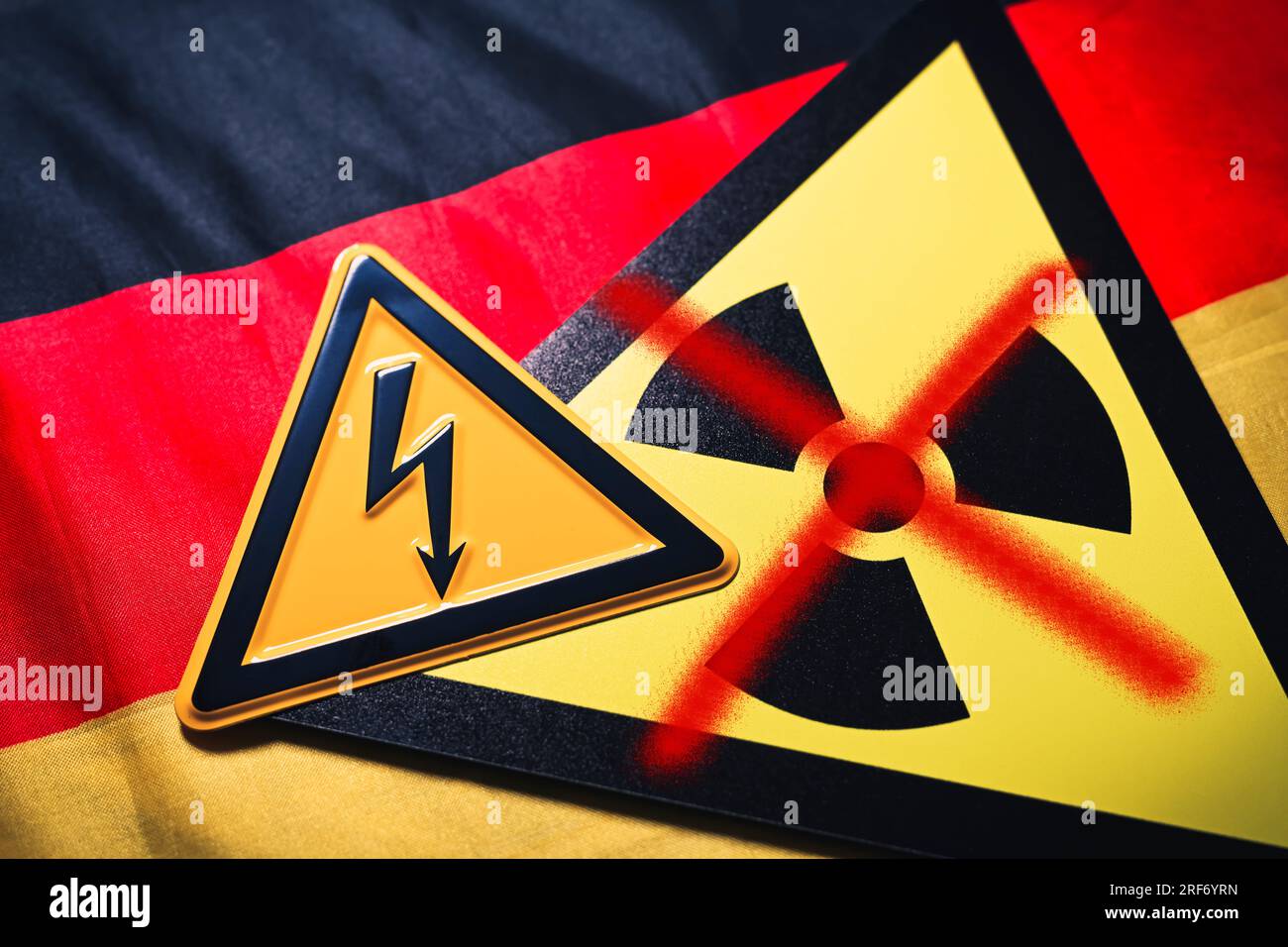 FOTOMONTAGE, Schild mit durchgestrichenem Radioaktivitätssymbol und Schild mit Strompfeil auf Deutschlandfahne, Symbolfoto für die AKW-Abschaltung Foto Stock