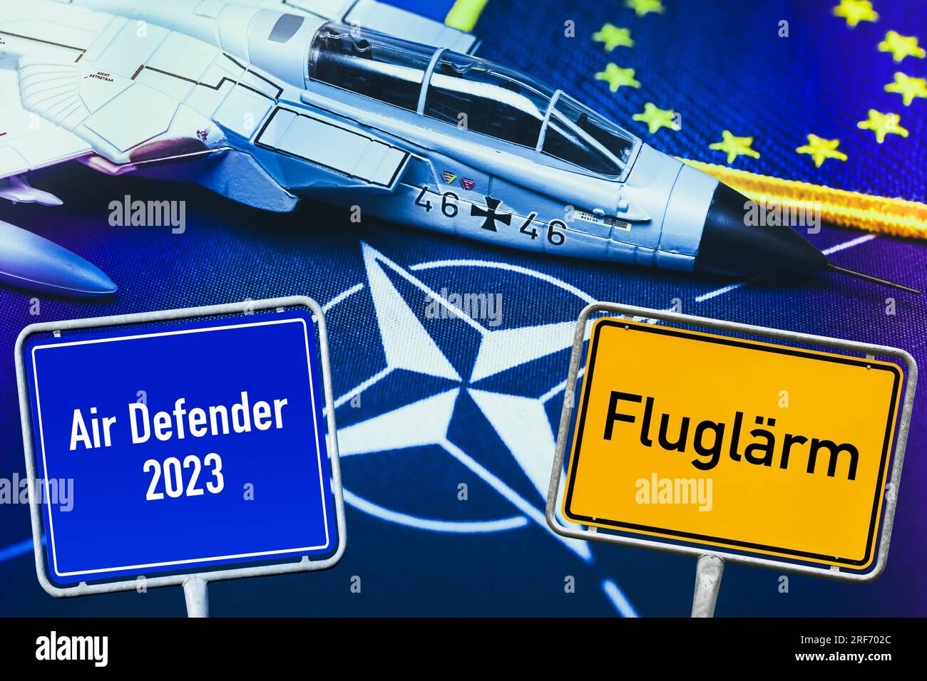 FOTOMONTAGE, Militärjetmodell auf NATO-Fahne und Schilder mit Aufschrift Fluglärm und Air Defender 2023, Symbolfoto NATO-Luftmanöver Foto Stock