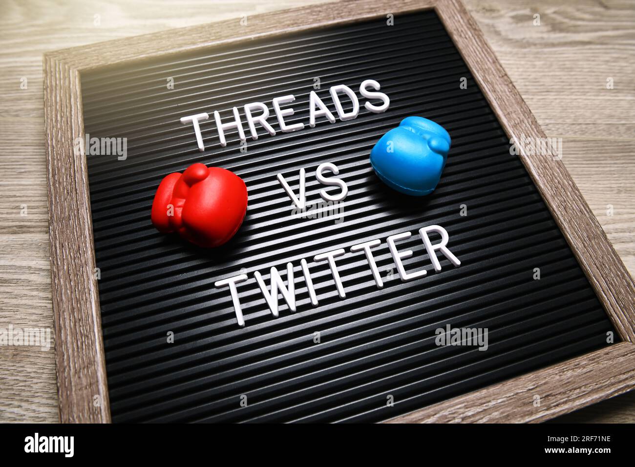 FOTOMONTAGE, Auf einer Tafel mit Boxhandschuhen steht threads vs Twitter, neuer Kurznachrichtendienst thread Twitter Konkurrenz machen Foto Stock