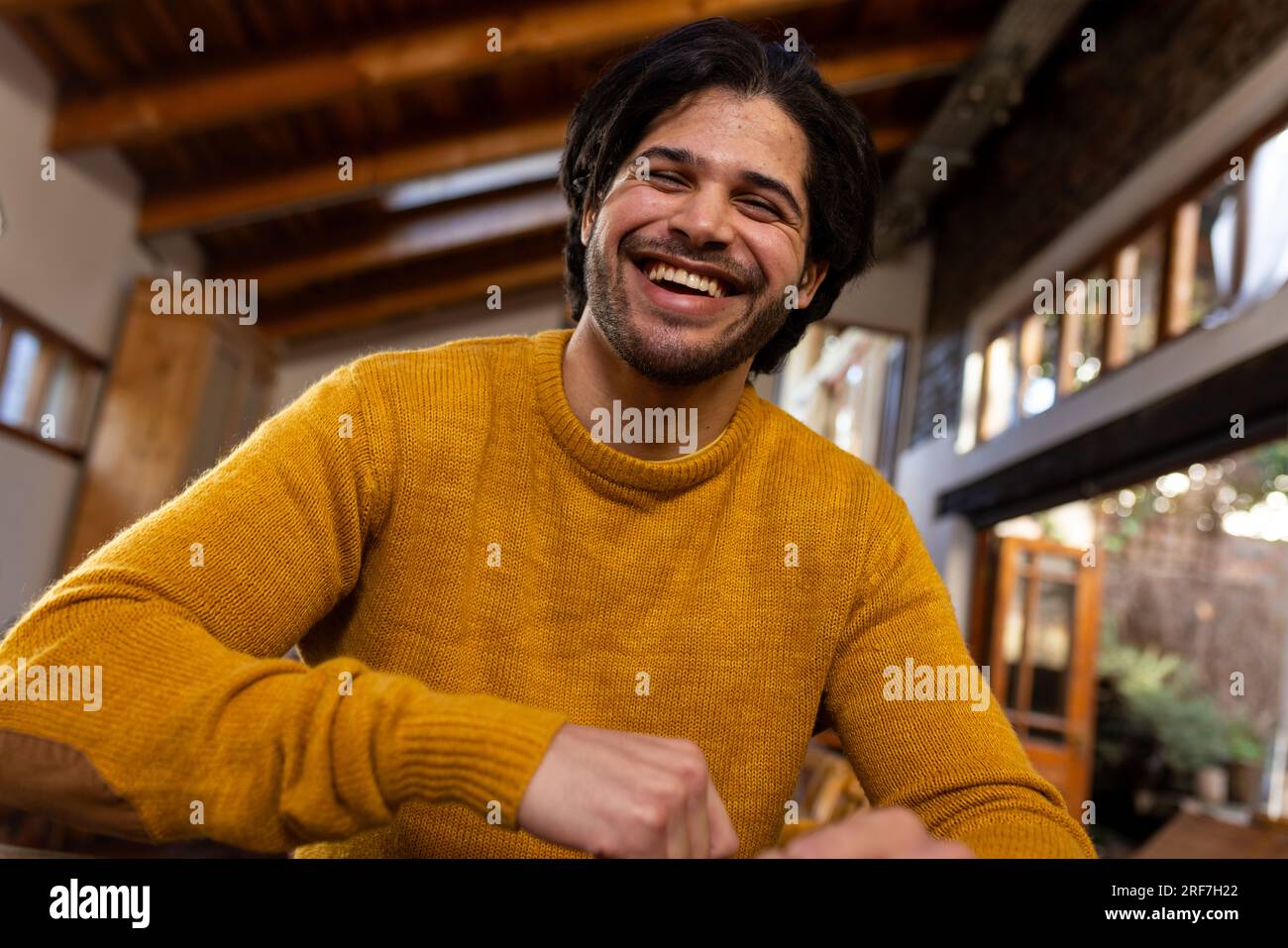 Un uomo indiano felice che fa videochiamata a casa soleggiata Foto Stock