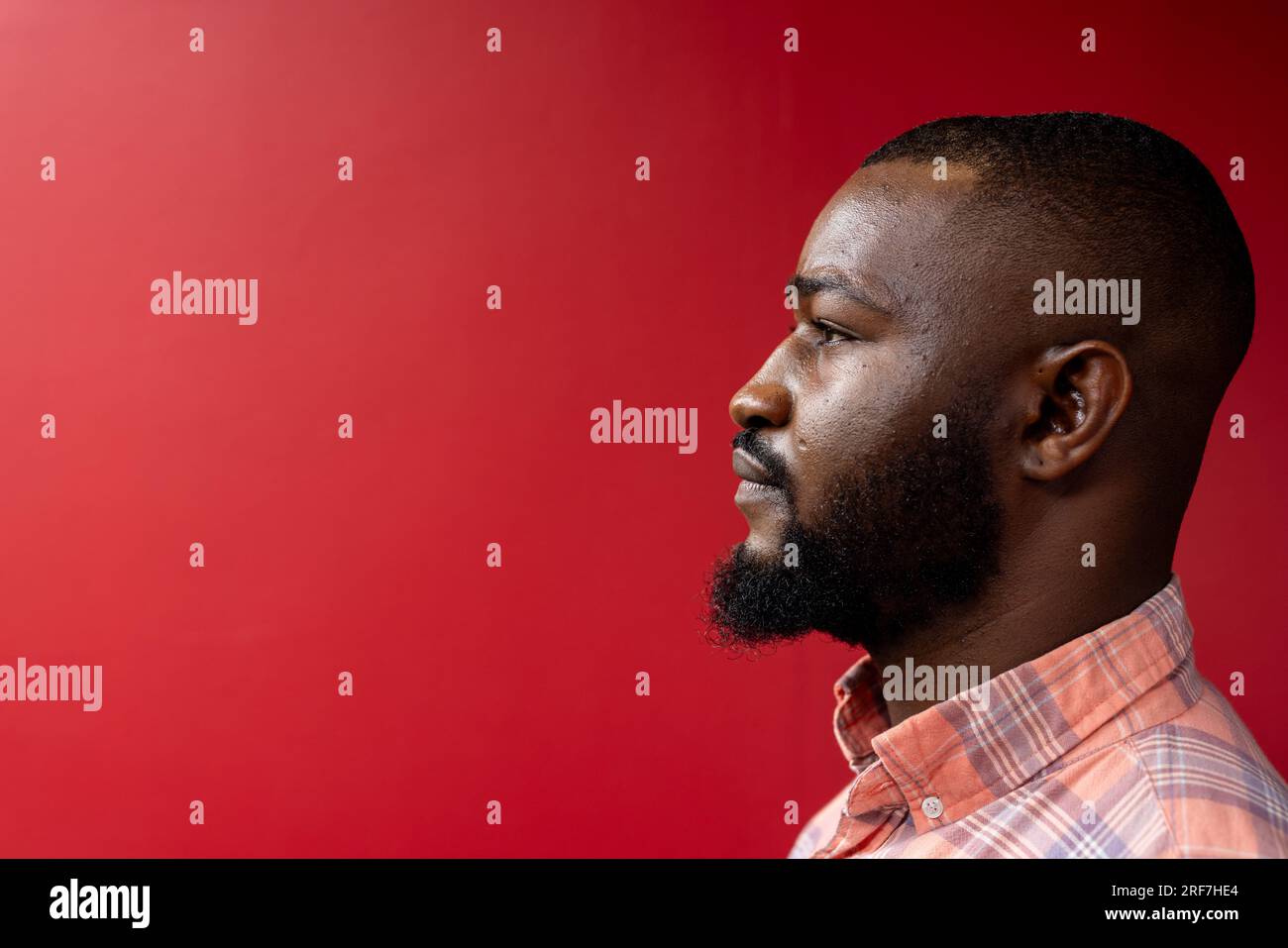 Vista laterale dell'uomo d'affari afroamericano su sfondo rosso, spazio copia Foto Stock