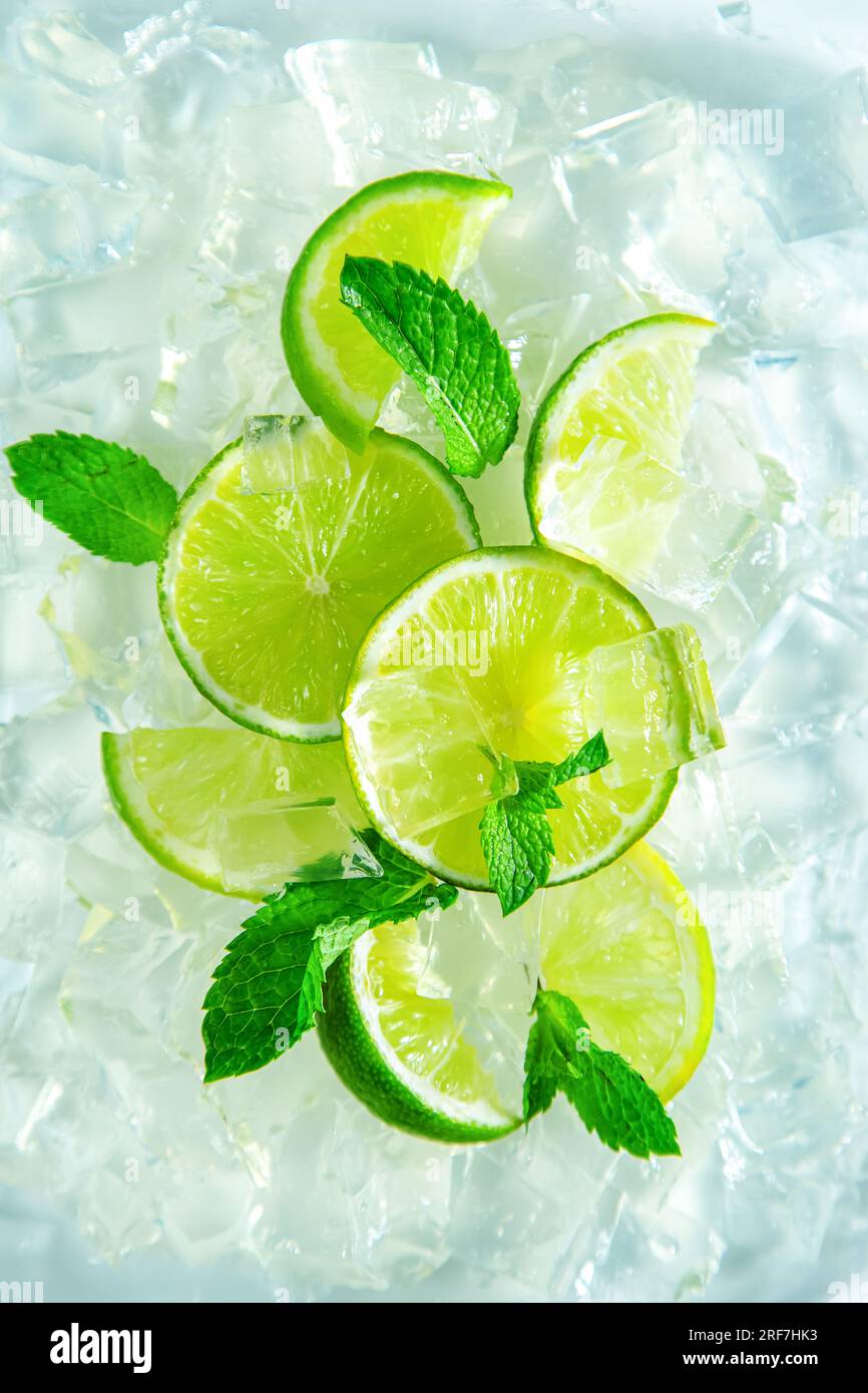 Spicchi di lime freschi e succosi con menta e ghiaccio. Vista dall'alto, primo piano. Foto Stock