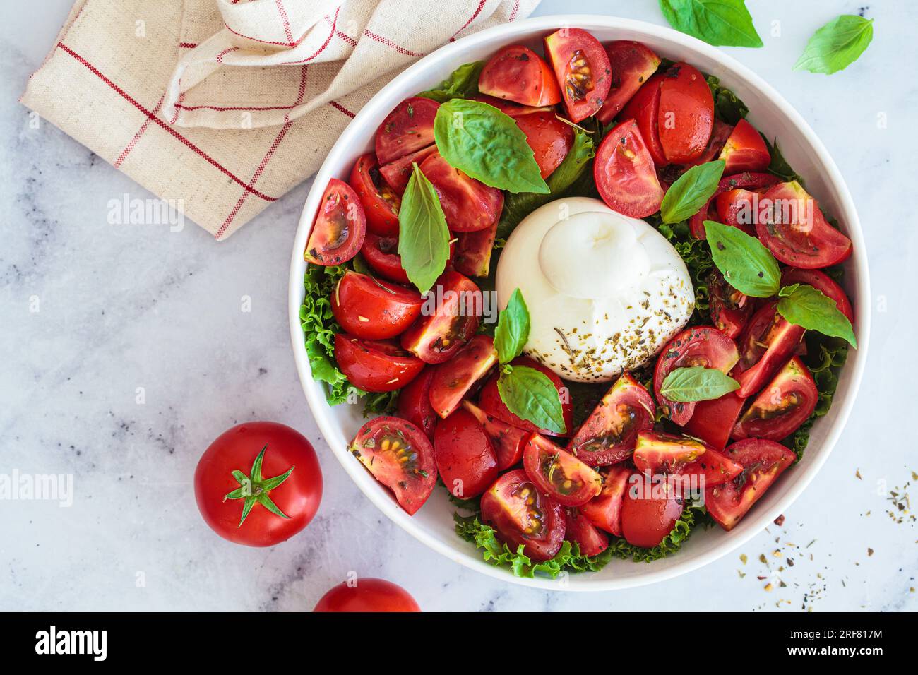 Insalata di burrata con pomodori e basilico in un piatto bianco, vista dall'alto. Foto Stock