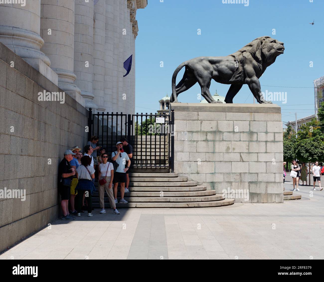 Persone in piedi all'ombra accanto al tribunale di Sofia (Sadebna Palata, o Palazzo di giustizia) nella città di Sofia, Bulgaria. 1° agosto 2023. Foto Stock