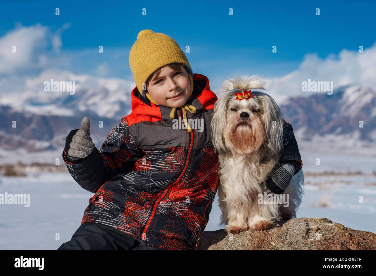 Bambino con ritratto invernale di cane shih tzu su sfondo montano Foto Stock