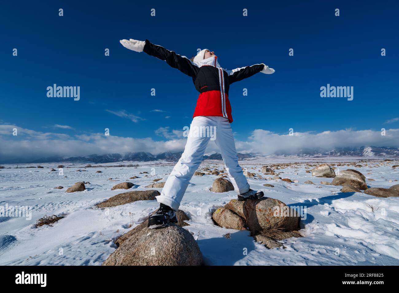 Giovane donna turista in piedi su pietre sullo sfondo del paesaggio montano invernale Foto Stock