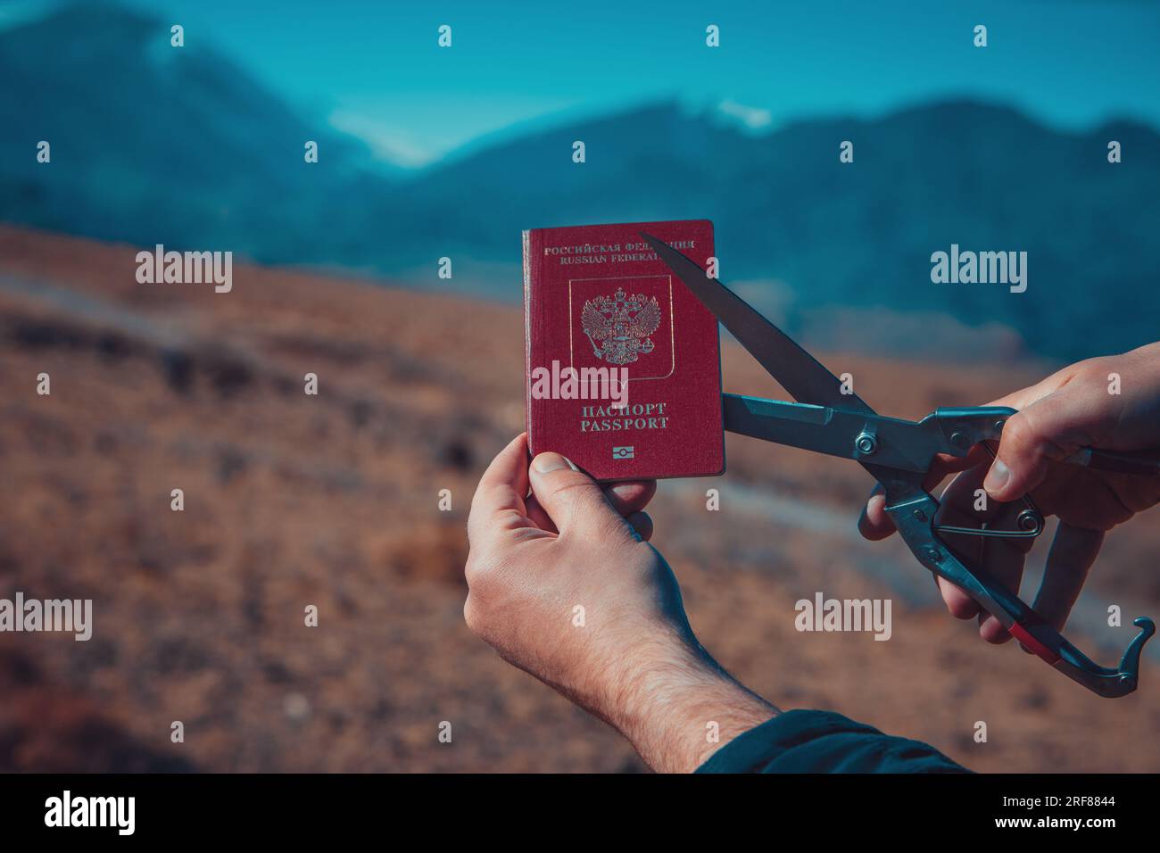 Uomo che taglia il passaporto russo sulle montagne, concetto di immigrazione Foto Stock