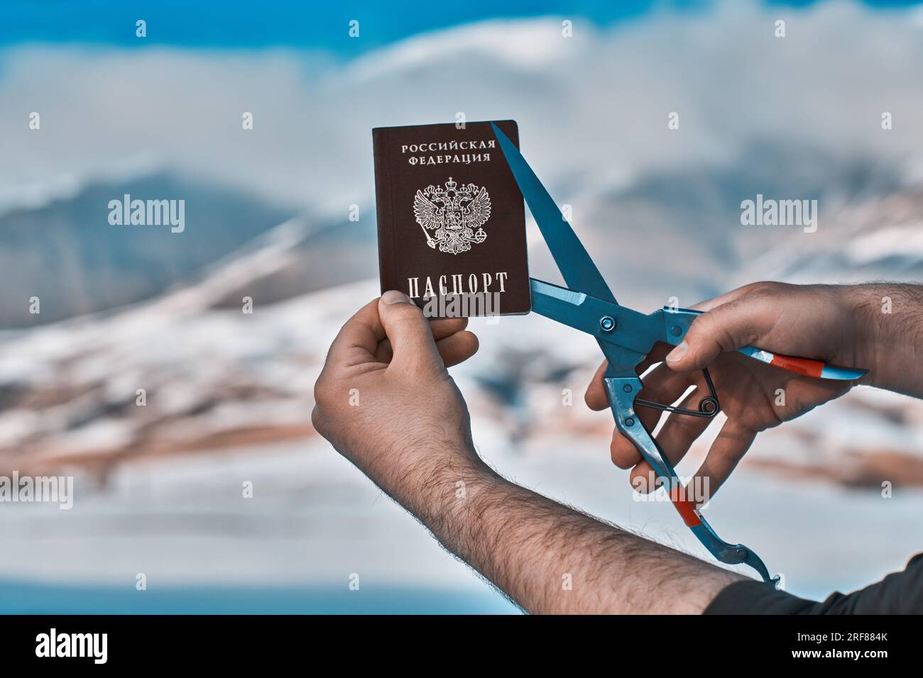 Uomo che taglia il passaporto russo sulle montagne, concetto di immigrazione Foto Stock