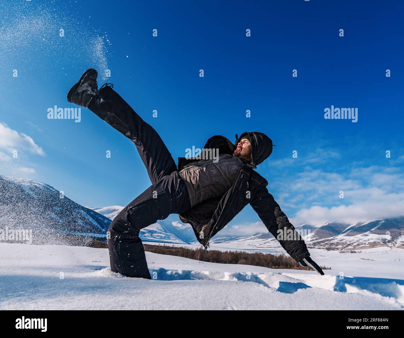 L'uomo scivolò e cadde nella neve profonda sullo sfondo delle montagne invernali Foto Stock