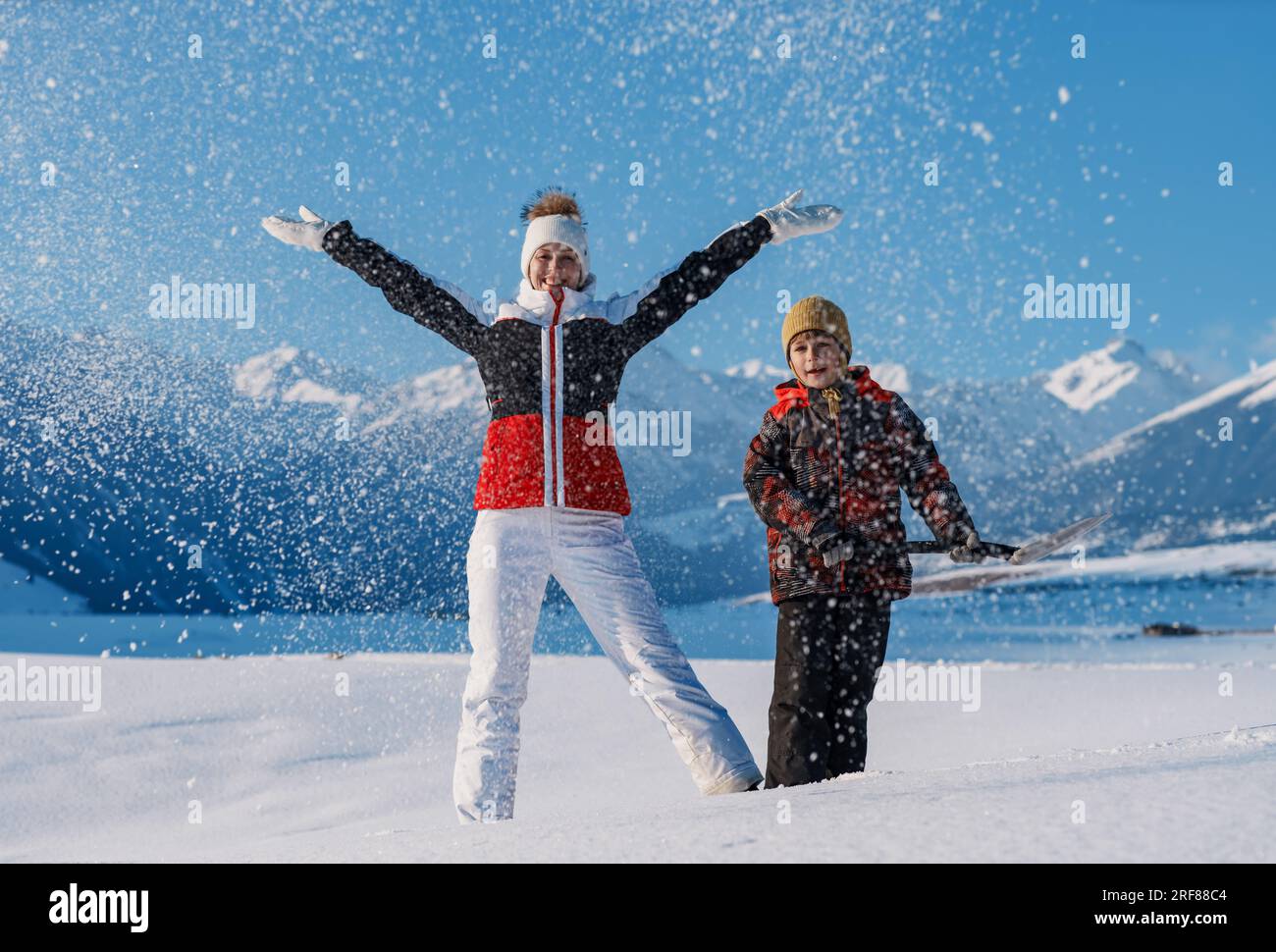 Donna e bambino con pala che si divertono sullo sfondo delle montagne invernali Foto Stock