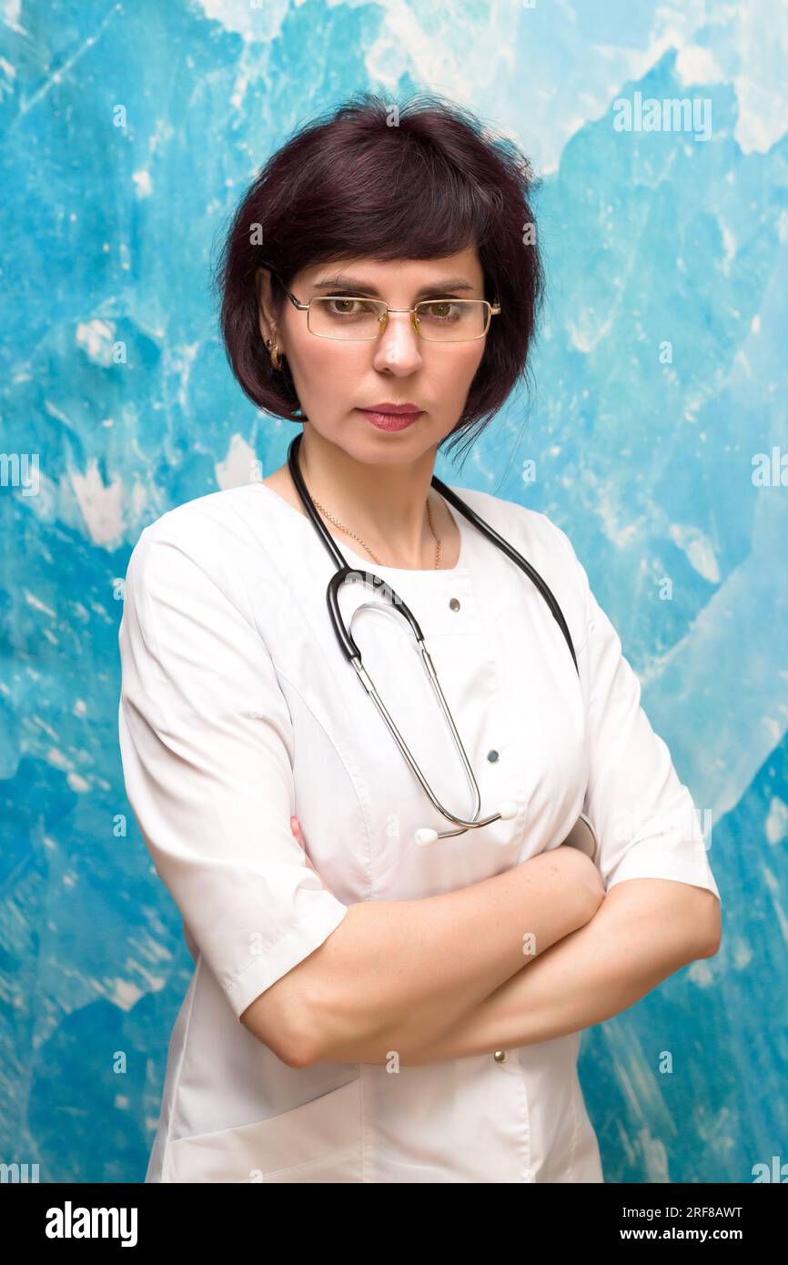 Ritratto medico donna di 40-44 anni vicino a una parete blu. Foto Stock