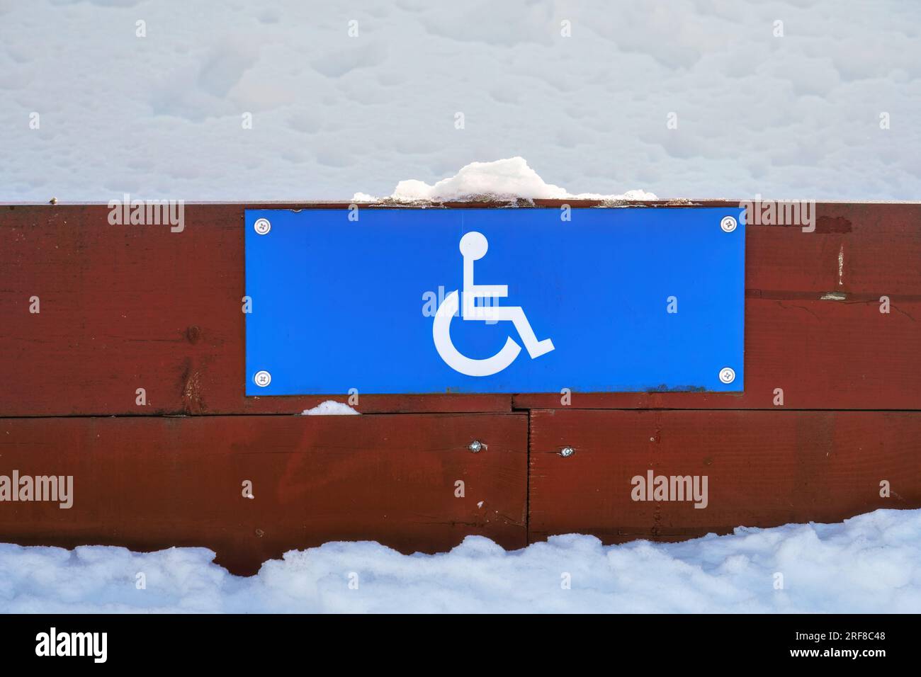 Cartello parcheggio per disabili su una recinzione di legno bassa in inverno, primo piano. Foto Stock