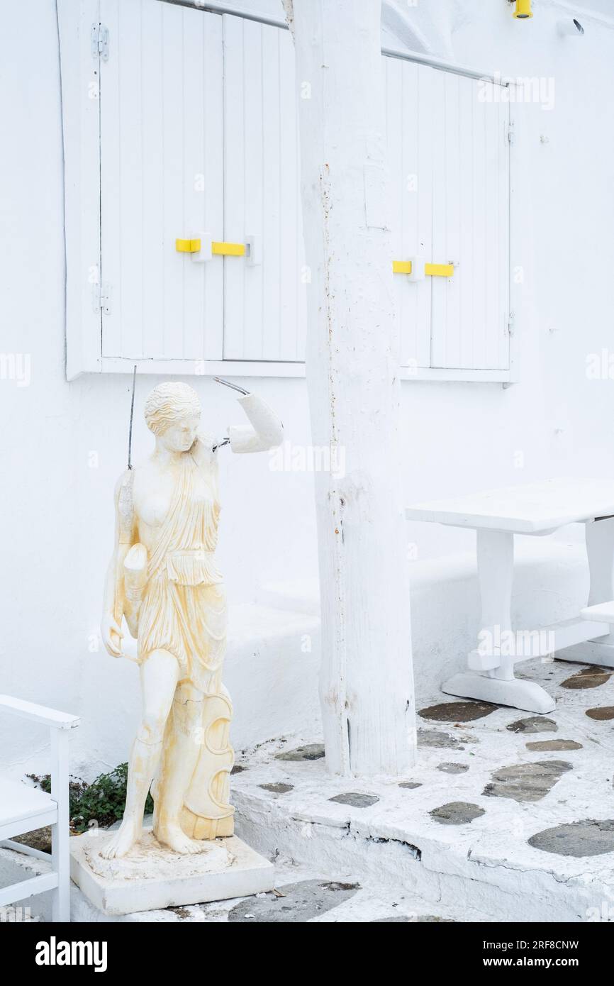 Fotografia di una statua con fili che spuntano dalla schiena e dal braccio, circondata da pareti bianche e persiane dietro. Foto Stock