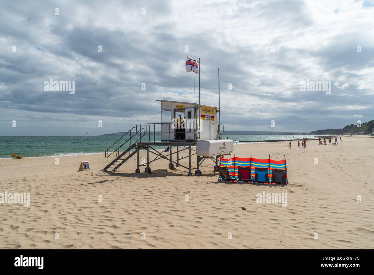 Alum Chine, Bournemouth, Regno Unito - 12 luglio 2023: Bandiera RNLI che sorvola il posto di guardia bagnino sulla spiaggia di fronte al mare. Foto Stock