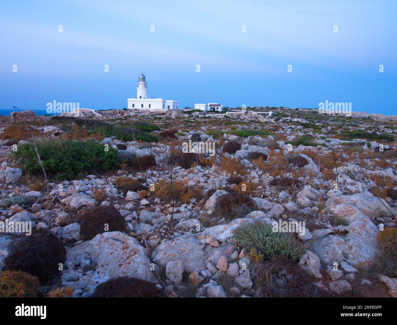 Un faro sull'isola di Minorca circondato da un terreno roccioso. Un faro de la Isla de Menorca rodeado de un terreno pedregoso. Foto Stock