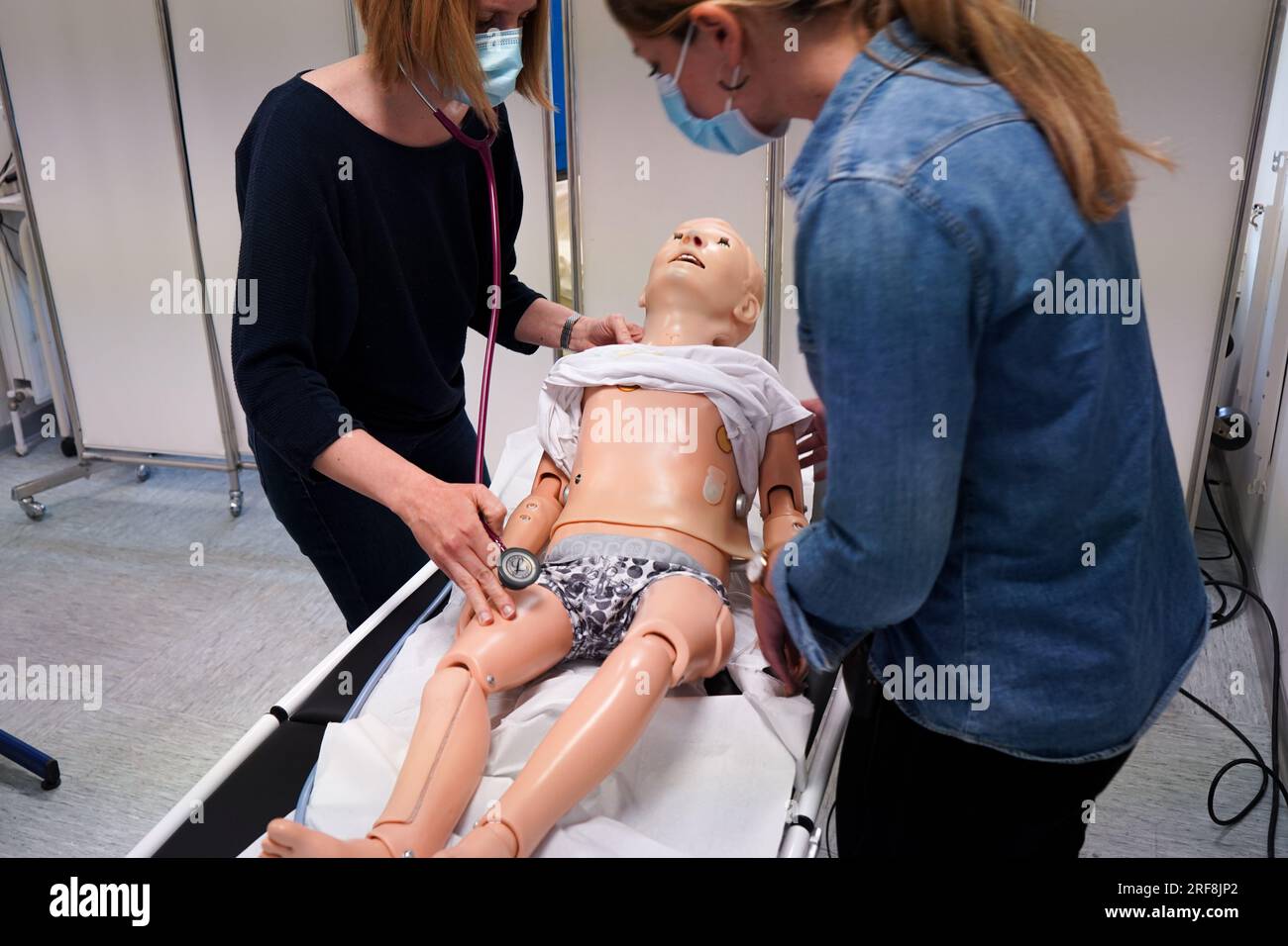 I medici generici sono addestrati alle procedure di emergenza pediatrica. Un medico svolge il ruolo della madre durante l'intervento. Foto Stock