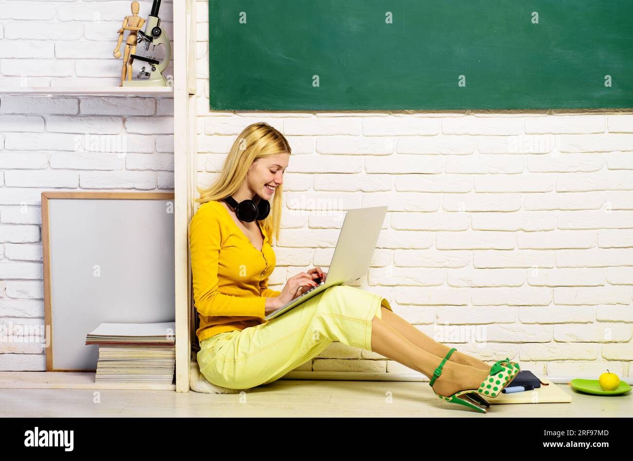 E-learning. Lezione e istruzione alle superiori. Studentessa sorridente seduta sul pavimento che si prepara per il test o l'esame a casa utilizzando un computer portatile. Parla, Internet Foto Stock