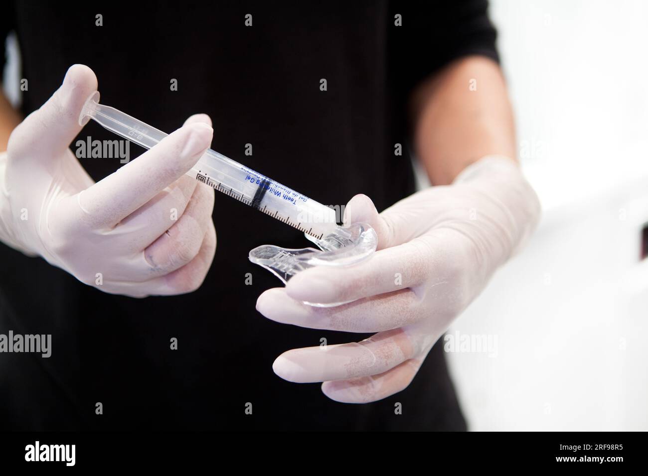 Sbiancamento dei denti applicando un gel in un vassoio ed esposizione a una lampada LED. Foto Stock