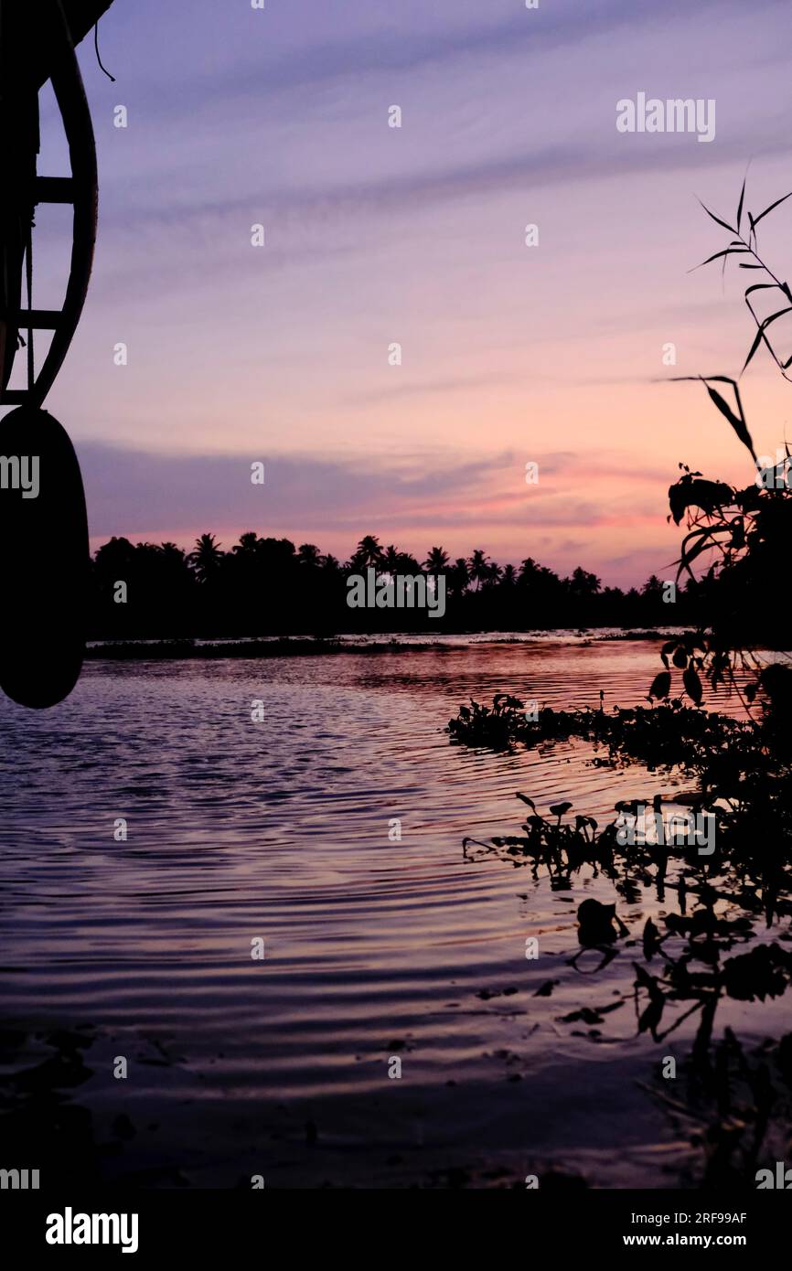 Ammira i colori del cielo dell'ora d'oro, catturati sulle acque del Kerala da una casa di barche Foto Stock