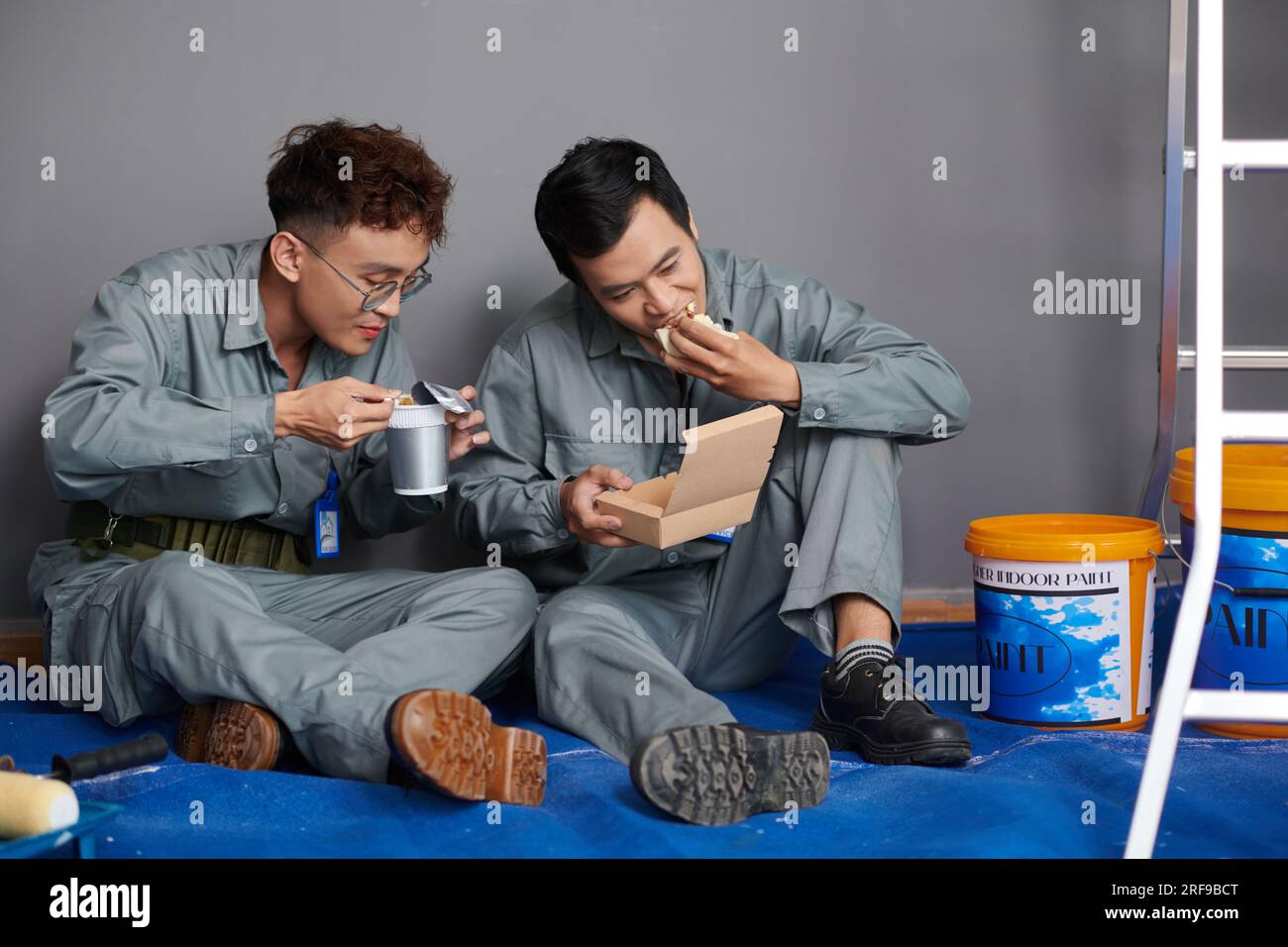 I lavoratori pranzano dopo aver dipinto le pareti in casa del cliente Foto Stock